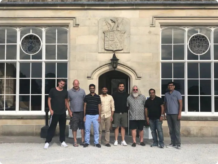 Diverse team of professionals at Augnito standing in front of historic building with ornate windows and coat of arms