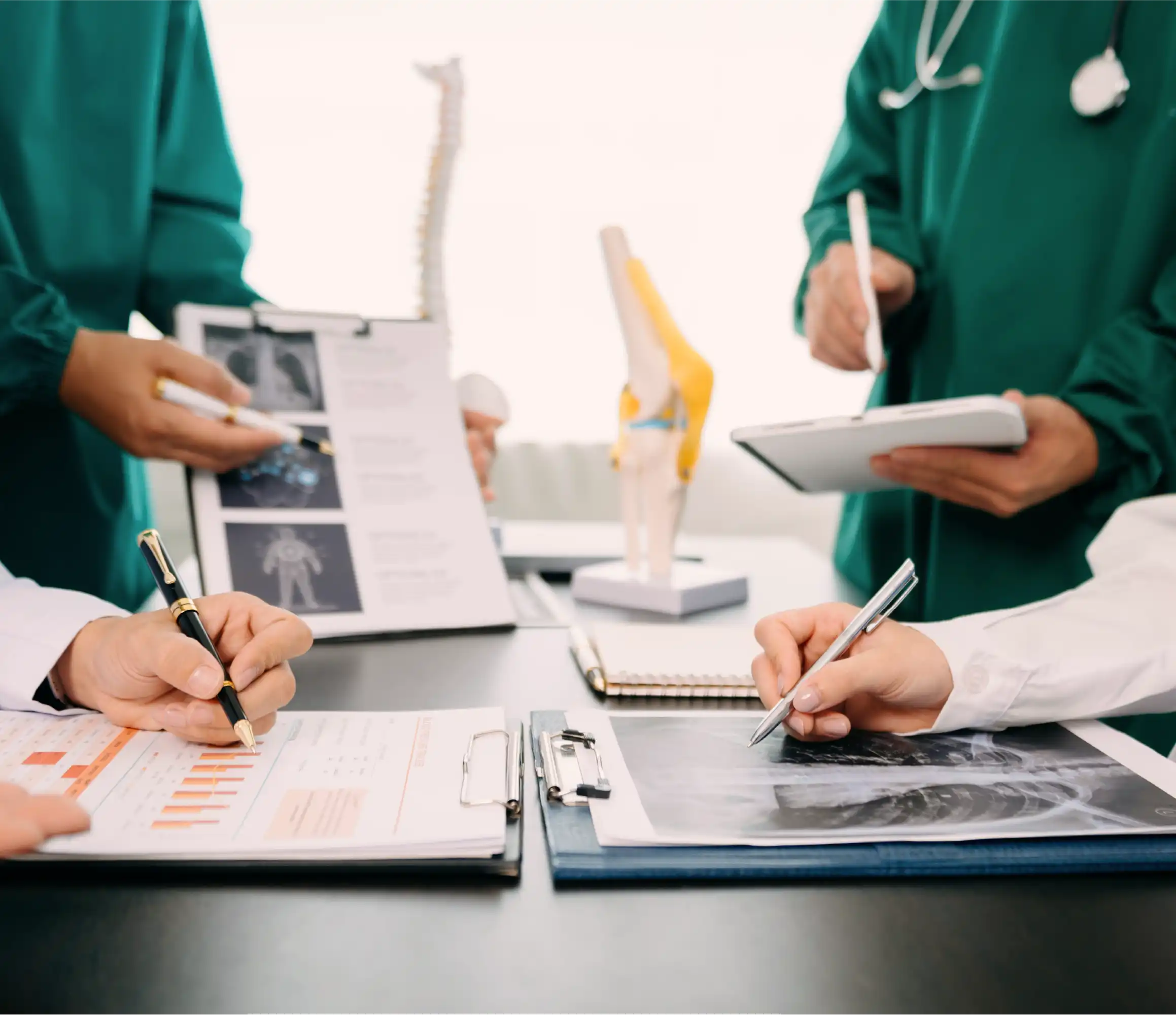 Medical professionals collaborating on clinical documentation, reviewing x-rays and data.