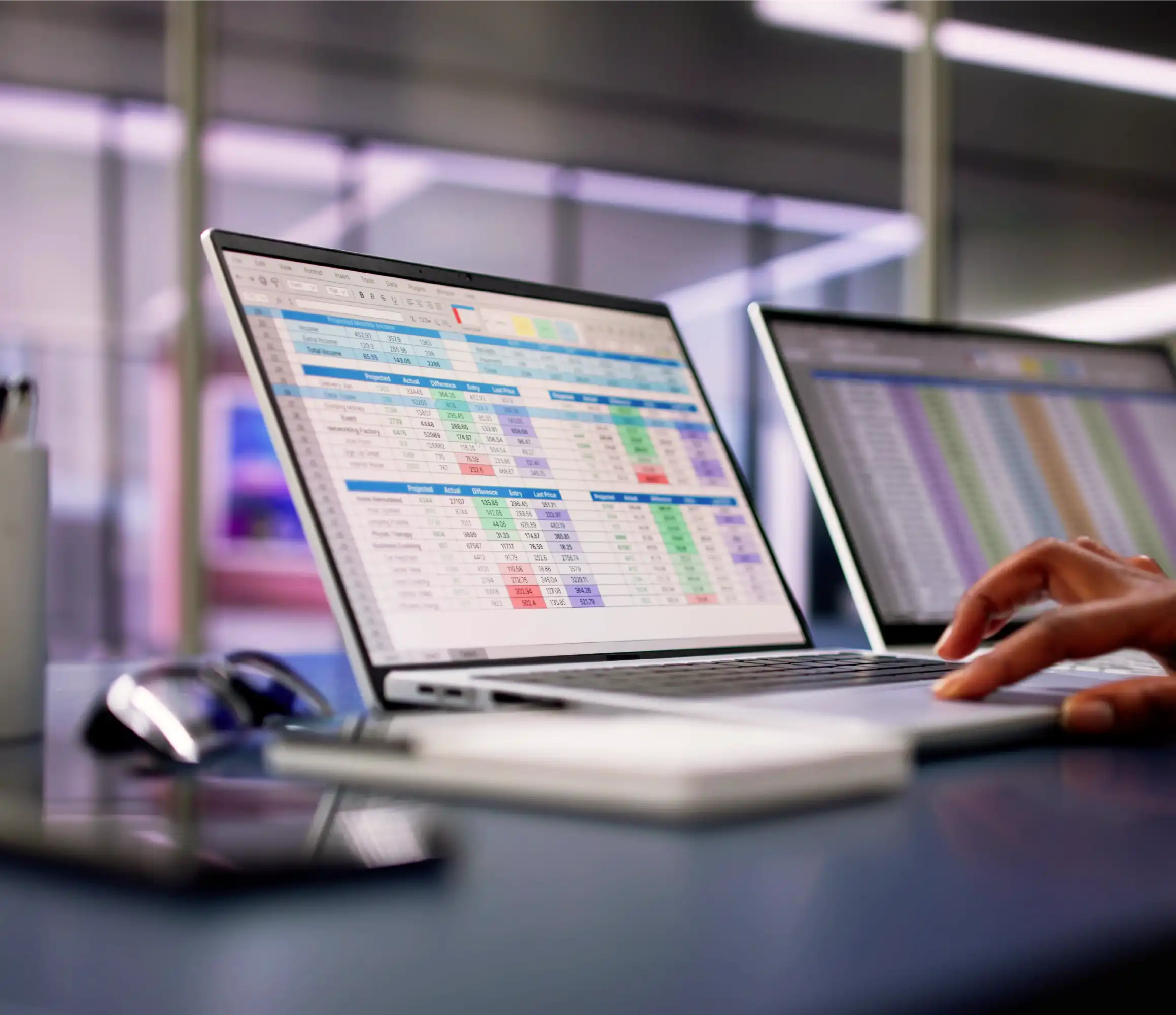 Laptops displaying colorful spreadsheets with medical data, hands typing, emphasizing efficient healthcare information management